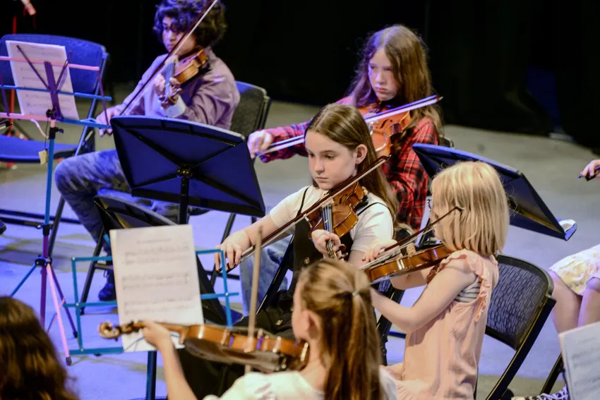 A number of children playing violin together