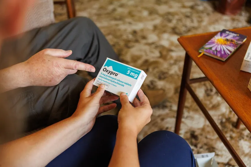 The hands of a nurse holding medicine and offering it to a patient