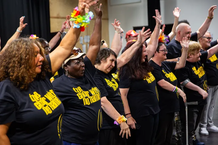 CWNN Liverpool choir memebrs in rehersal singing with thier arms in the air