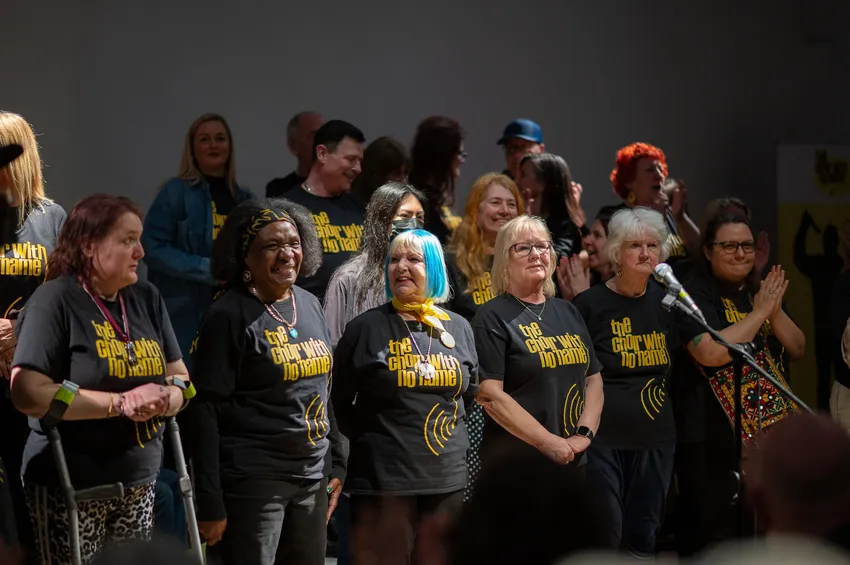 CWNN Coventry choir members smiling on stage at a performance