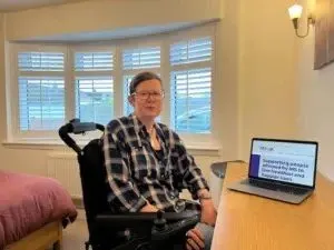Lisa, helpline client, sitting at a desk in her bedroom with a laptop in front of her