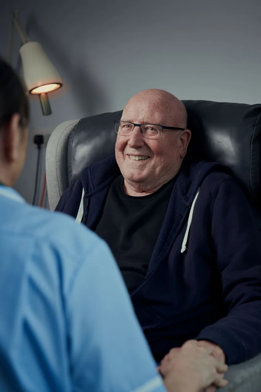 Man sitting in chair, smiling and nurse in uniform
