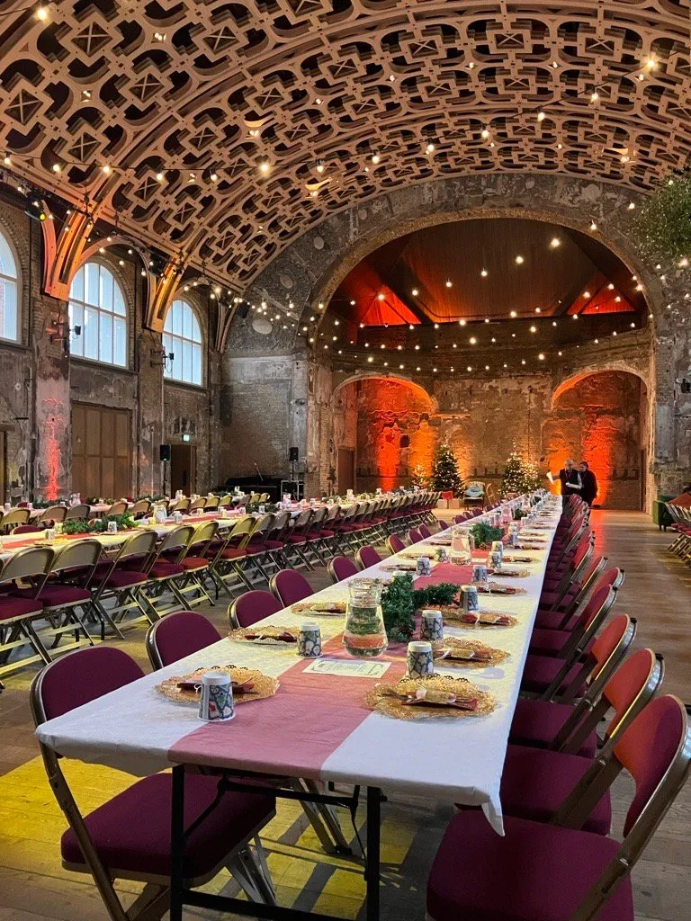 Festive banquet tables prepared for Community Christmas Day 2023 in the Grand Hall, with festive table settings and warm lighting, image credit Meg Khor