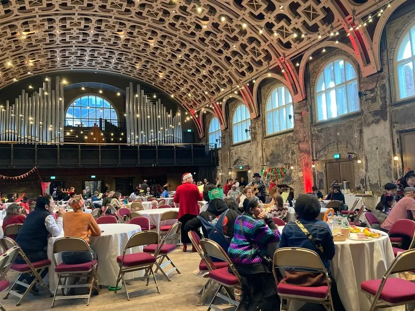 Guests gather around several round tables in the Grand Hall for Community Christmas Day 2022, image credit Miran Hadzic