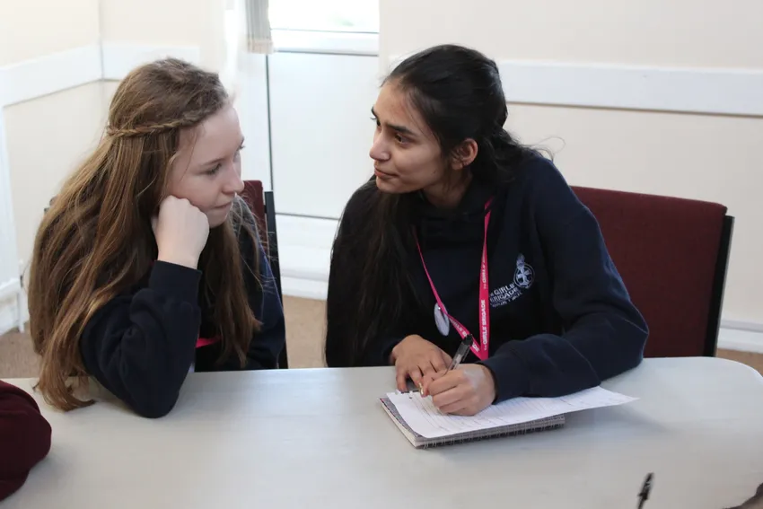 Two girls making notes and chatting together