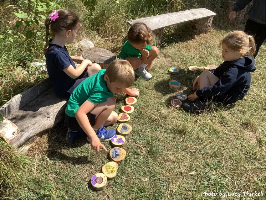 Children taking part in a hands-on outdoor learning activity, using nature-themed wooden resources to explore wildlife and learn together.