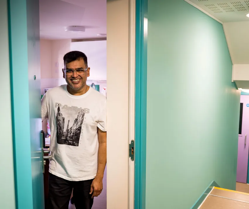 A resisdent smiling at the door to his home