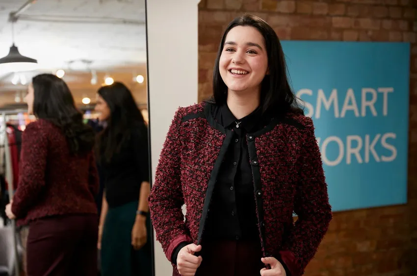 A Smart Works Scotland client smiles as she looks at herself in an interview outfit provided by Smart Works Scotland.