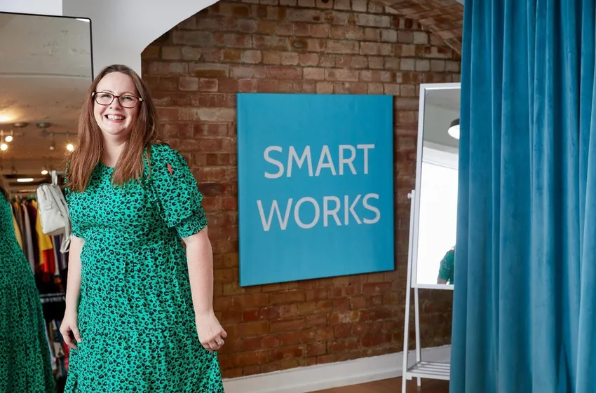 A Smart Works Scotland client smiles as she looks at herself in an interview outfit provided by Smart Works Scotland.