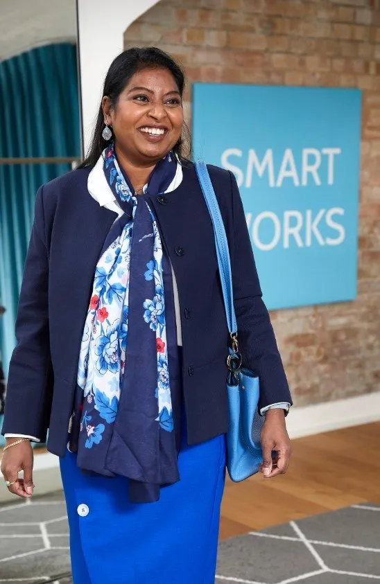 A Smart Works Scotland client smiles as she looks at herself in an interview outfit provided by Smart Works Scotland.