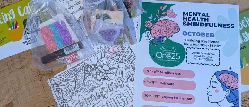 Mindfulness resources are spread out on a table. They include sweets, stickers, puzzles, colouring sheets and a poster for 'Mental Health & Mindfulness October' at One25