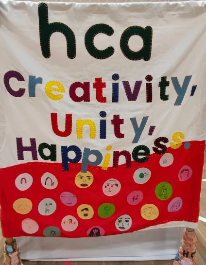 Image of community banner with messages of creativity, unity and happiness
