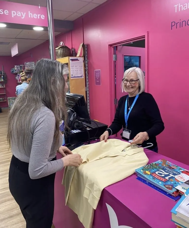 A volunteer serving a customer at the till in a Princess Alice Hospice charity shop
