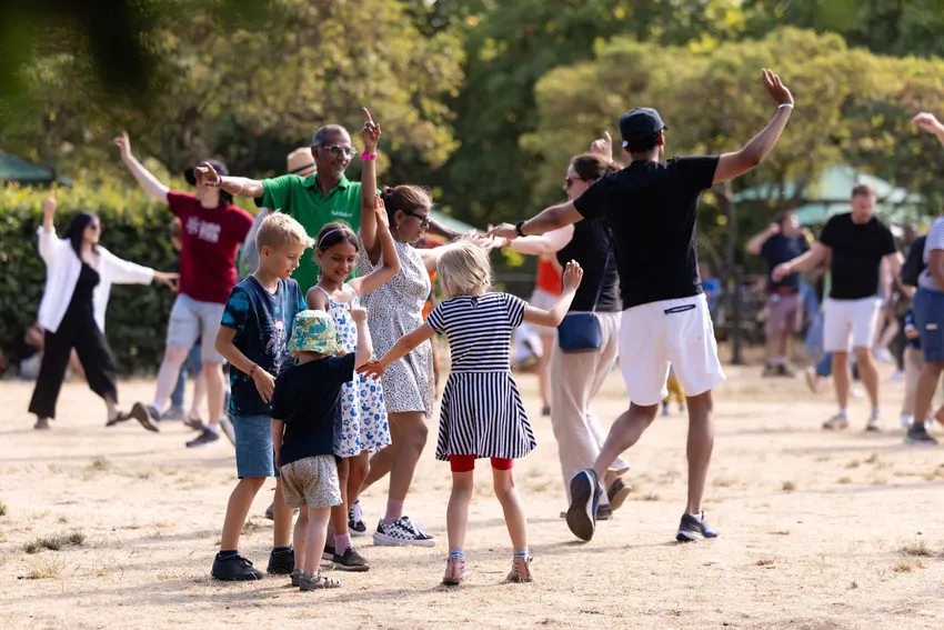Children and adults dancing together in a park. EFDSS Bhangra Ceilidh, Greenwich Park, July 2025. Image credit Arts Trust, Summer in Greenwich Park. Photographer Roswitha Chesher.