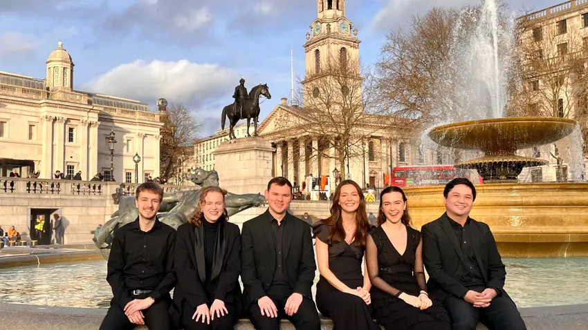 St Martin-in-the-Fields Emerging Artists wearing all black enjoying a bright summer's day after a concert at the Trafalgar Square in London.