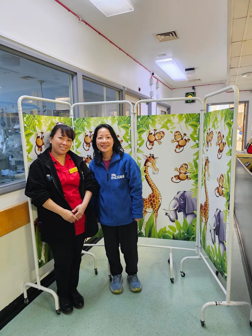 Ickle Pickle staff member and a neonatal staff member in front of privacy screens donated by the charity