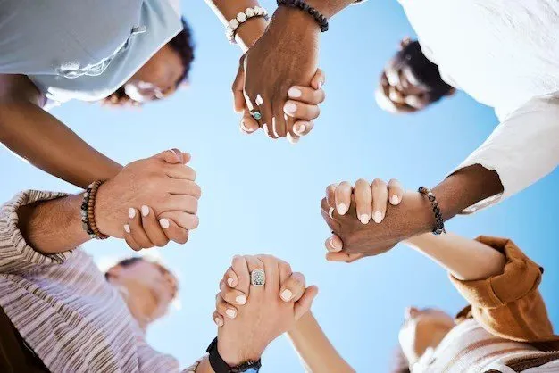 Group of people holding hands in a circle, supporting one another