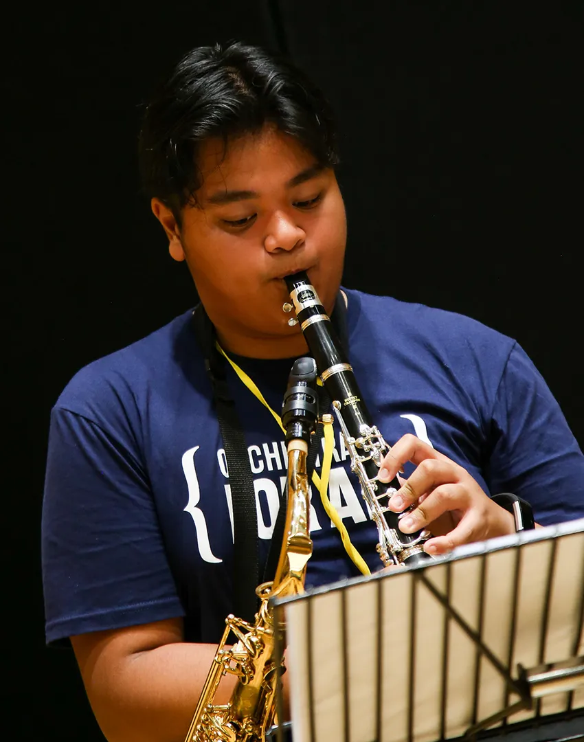 A young person in a blue T shirt playing the clarinet