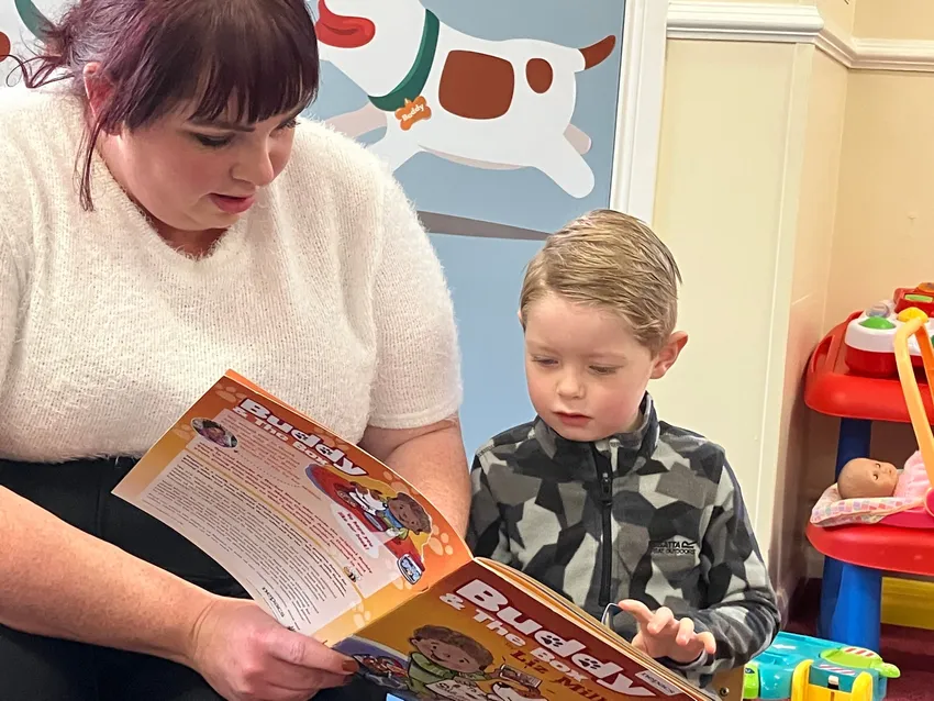 A Nepacs play worker reading the Buddy and the Box book with a young child