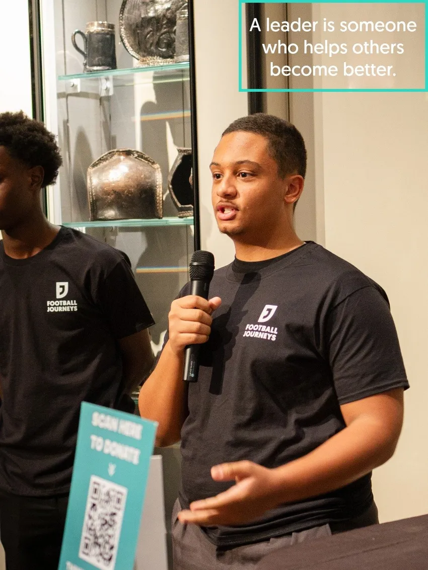 One of FJ's teenage ambassadors holds a microphone and introduces himself to the audience at our celebration event