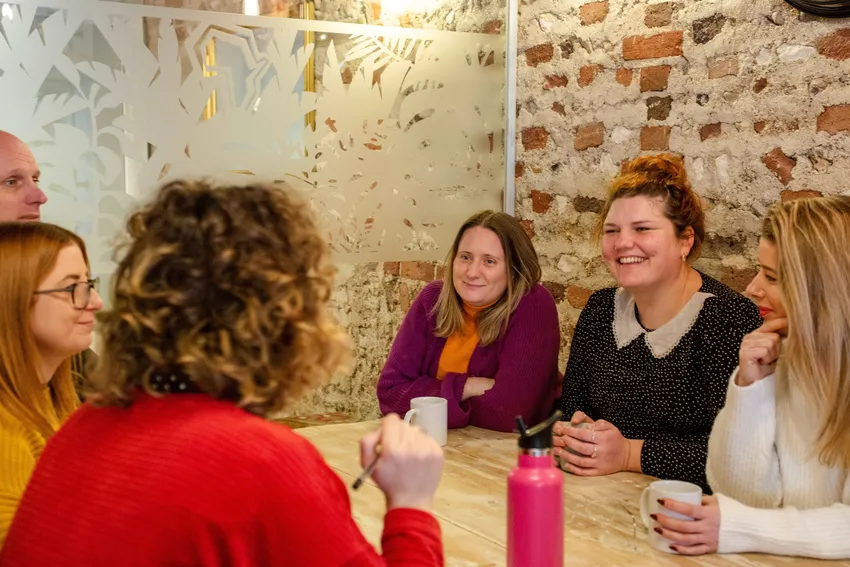 Justlife staff working around a table at the Justlife Hub in Brighton, smiling.