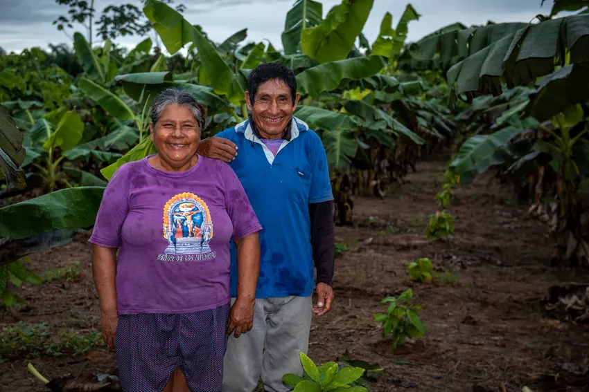Farmers smiling in front of their reforested plot