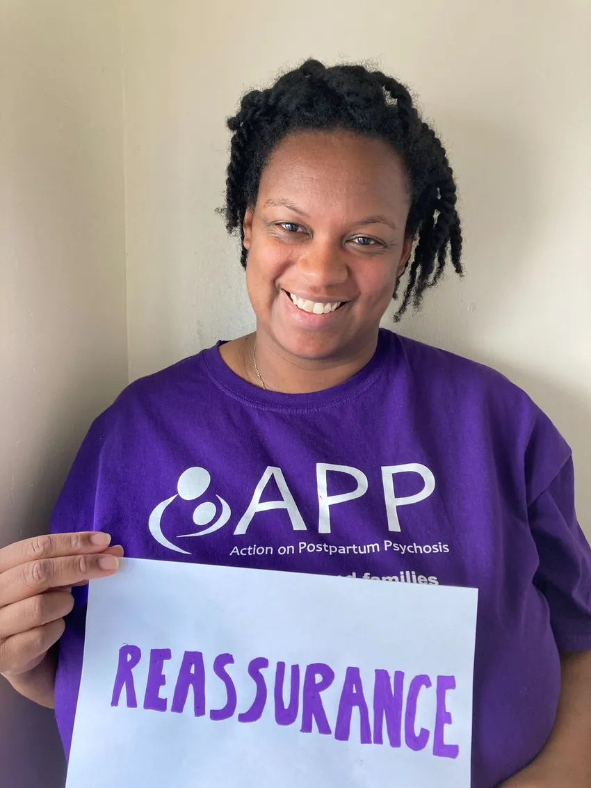 A woman holding a sign saying 'reassurance'