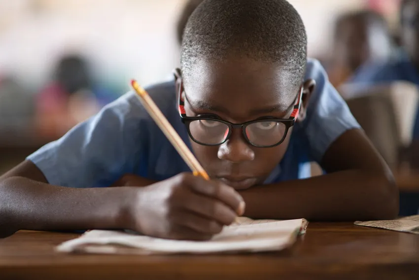 A young boy learning in class thanks to his new glasses, provided by ZOA.