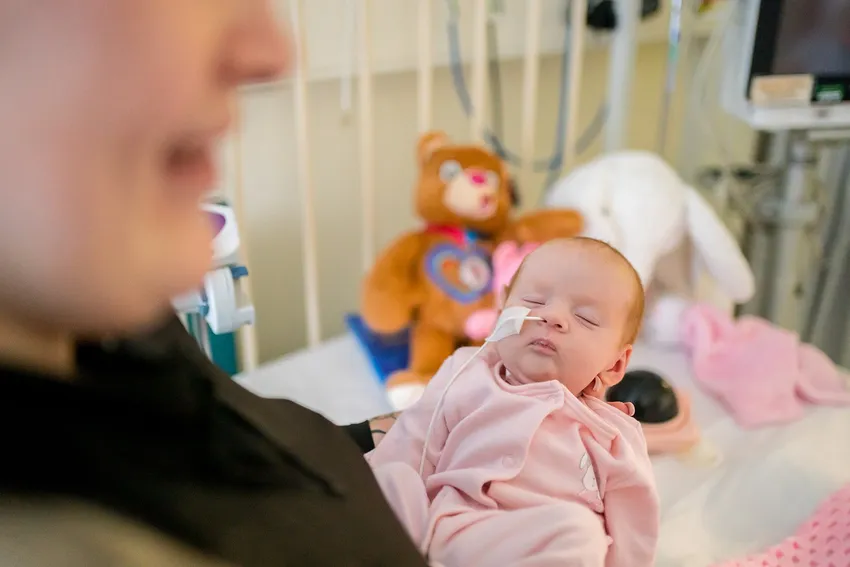 Baby dressed in pink with a feeding tube in hospital