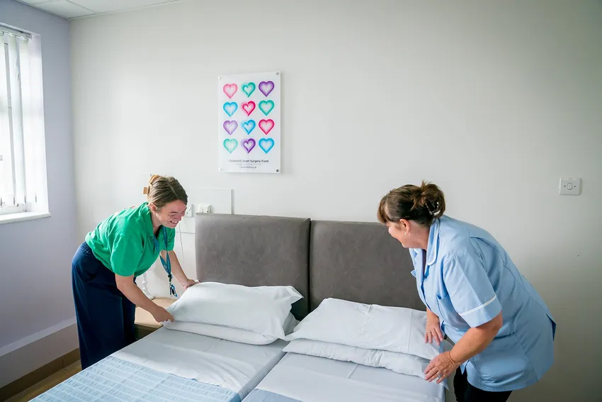 Head of Family Support and housekeeper making the bed in family accommodation