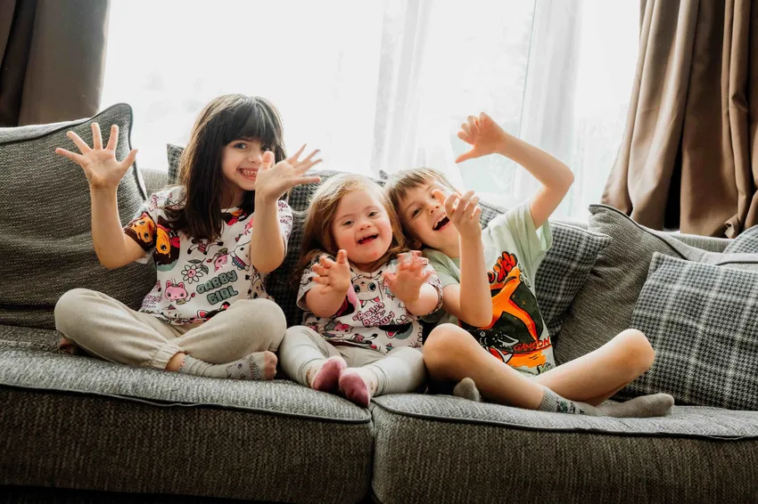 Three children sat on a sofa in their pyjamas.