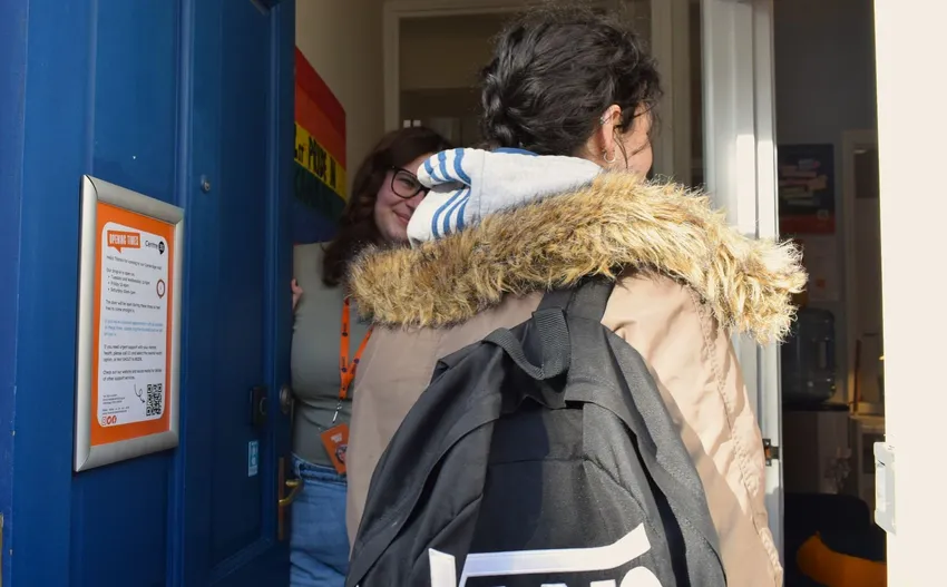 A Centre 33 team member welcomes a young person into the hub, greeting them at the door as they arrive for support.