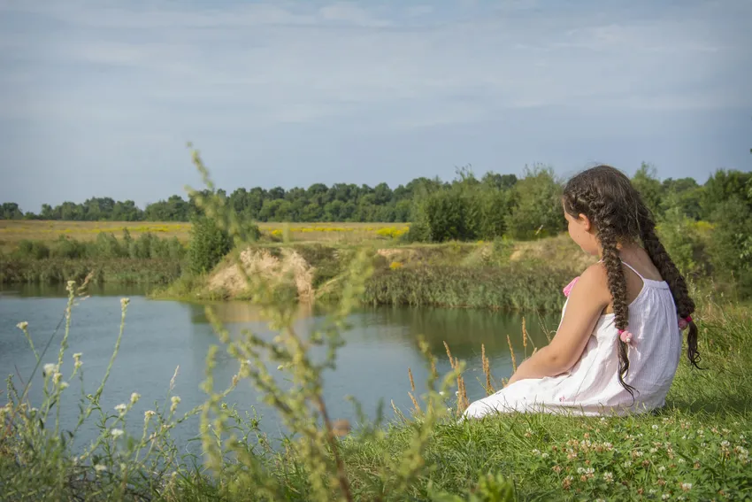 Young girl sitting peacefully by a river