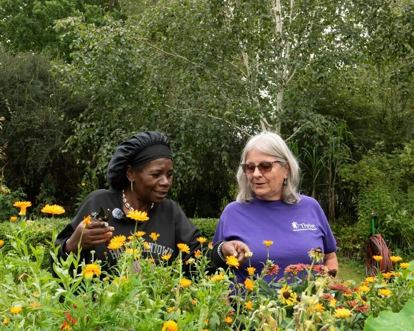 Client gardener, Ciceley, is dead heading flowers with practitioner, Sharon.