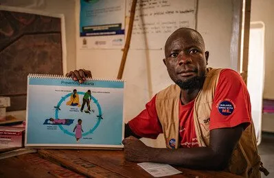 Health worker, Emmanuel, holds an instructional manual about Malaria prevention.