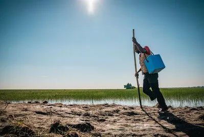 Health worker Emmanuel often wades through swamps with a single walking stick, navigating deep mud and unstable ground.