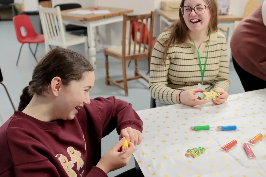 Two girls enjoying Christmas biscuit decorating at a Christmas party