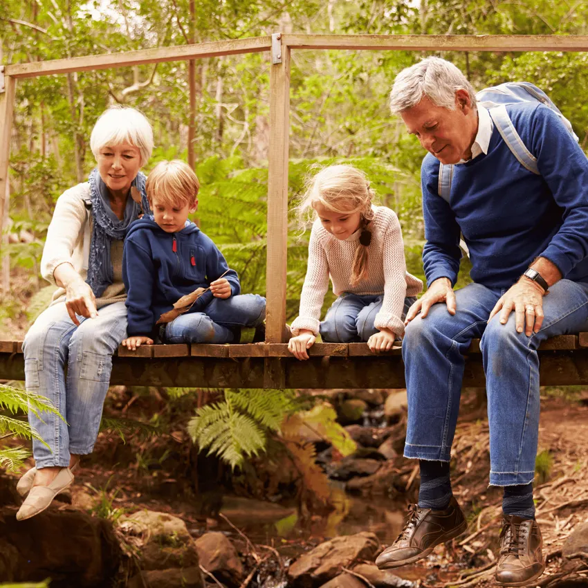 Grandparents with young boy and girl sat on bridge
