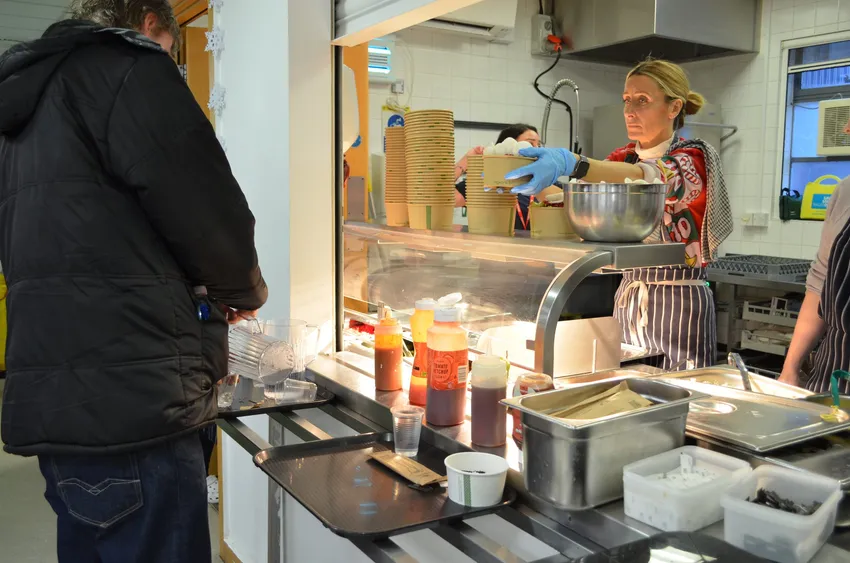 Female kitchen staff member serving food to one of our male clients