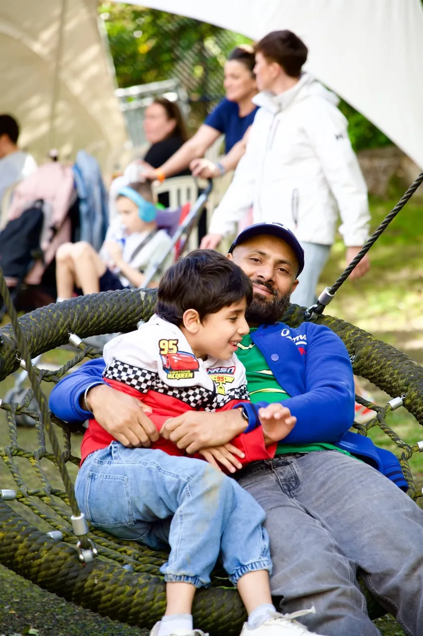 Dad and son smiling together on a bucket swing
