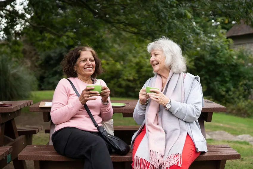 Two laughing women sit together and pass a device (1)