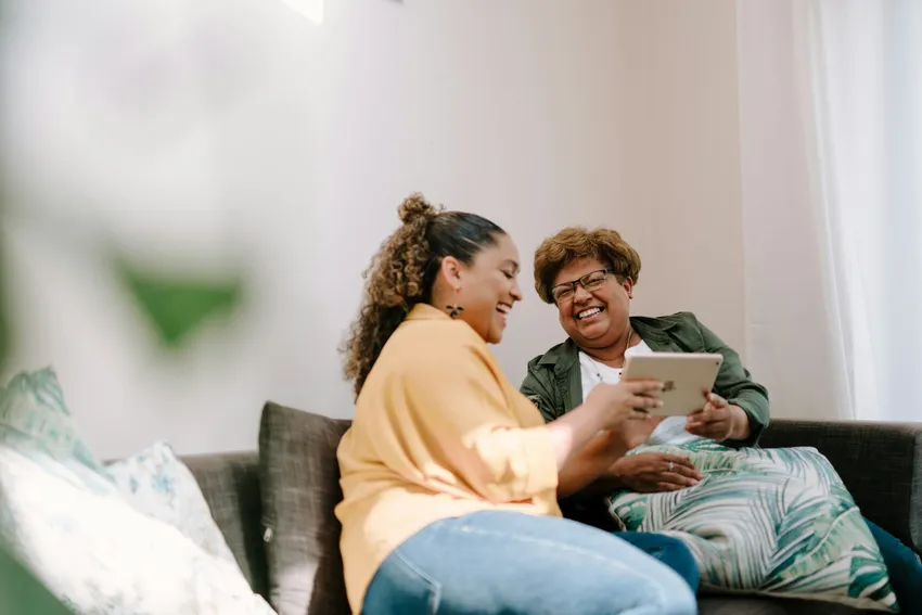 Two laughing women sit together and pass a device (1)