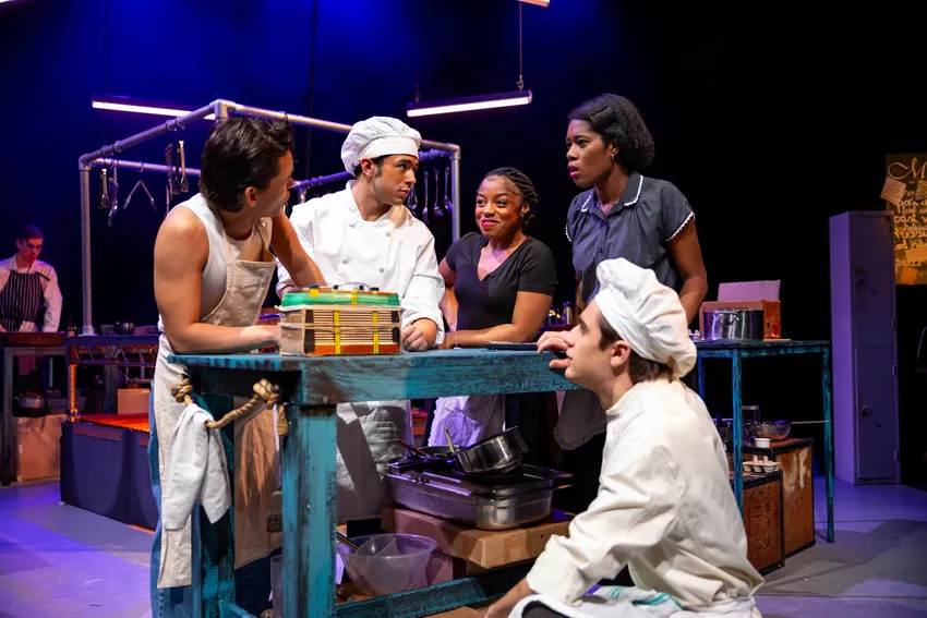 a student production of 'The Kitchen' with students dressed as chefs and servers