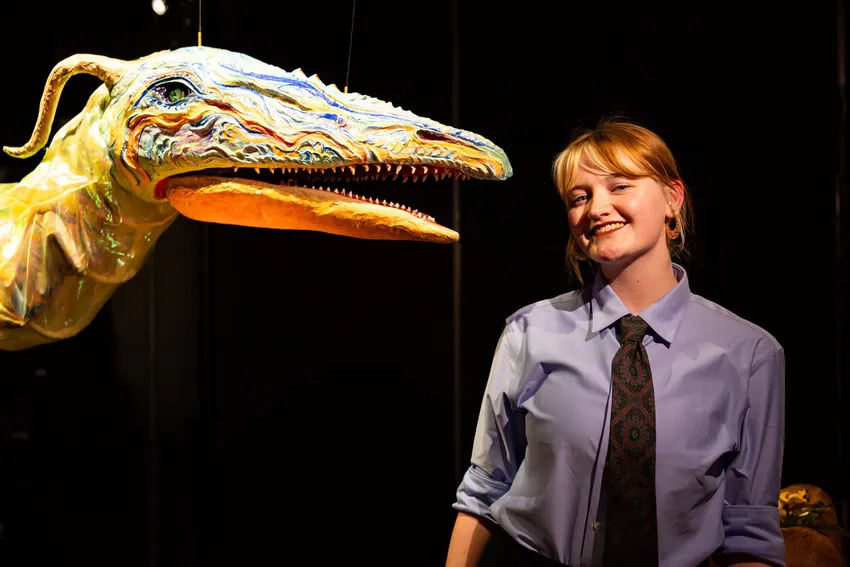 A student standing next to a large puppet dragon she has made