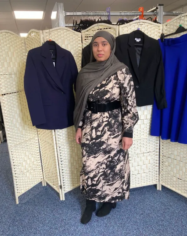 Smart Works Reading client Nadia stands in the dressing area wearing her new interview outfit provided by Smart Works Reading.