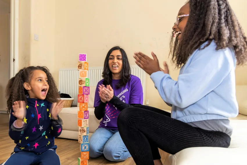 Home-Start volunteers plays with children as they stack building blocks