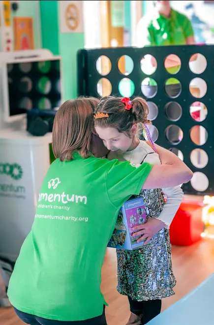 Young child in a sparkly dress with a member of the Momentum team