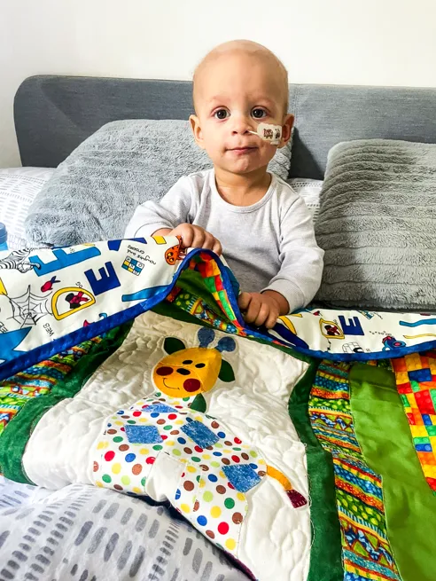 Young boy with a gifted quilt sewn by Momentum volunteers