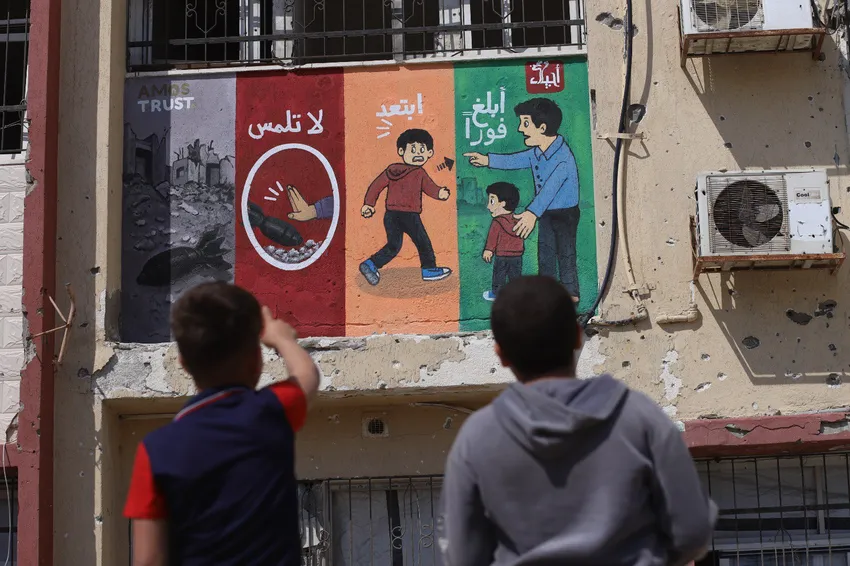 Children looking at Unexploded Ordinance Warning mural in Gaza City