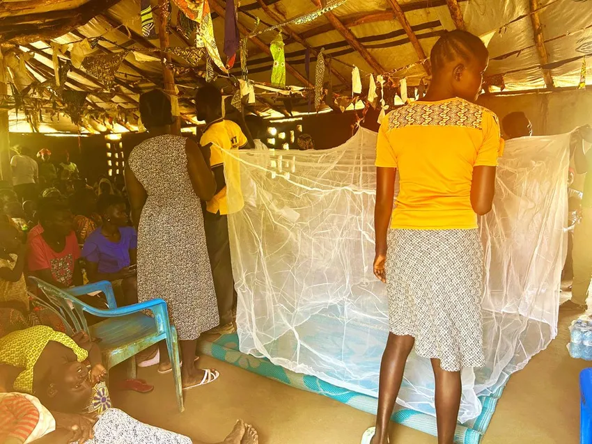Mothers being shown how to hang mosquito net